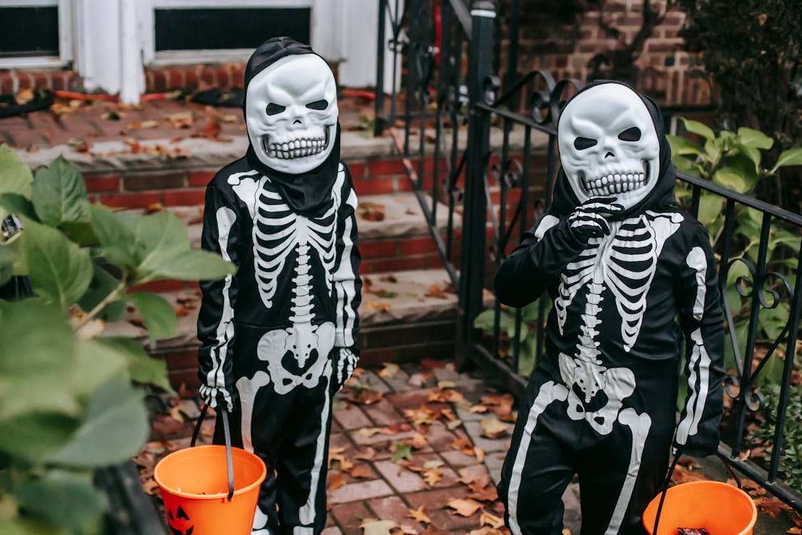 Unrecognizable kids in Halloween costumes standing near house