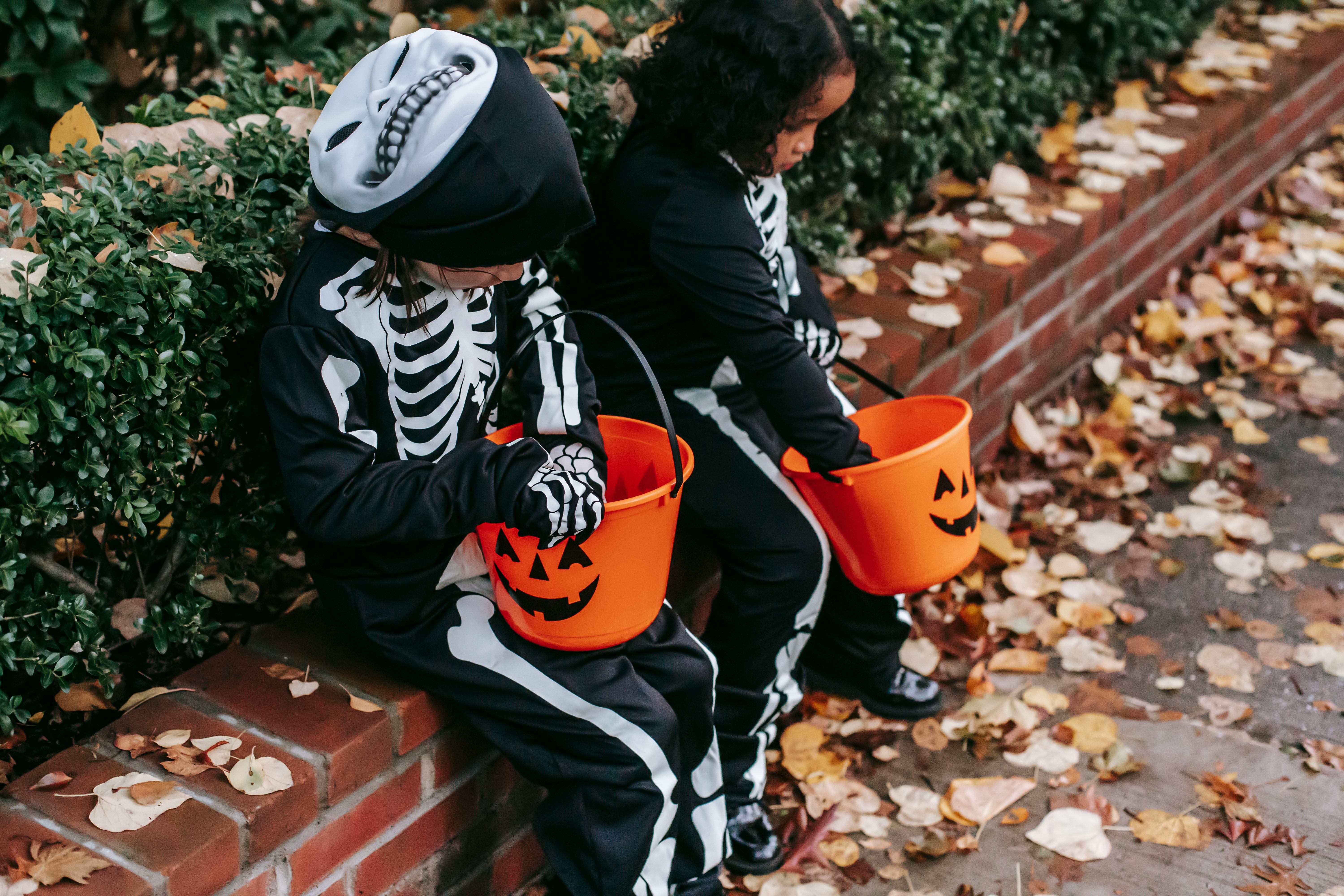 anonymous multiracial children in skeleton costumes trick or treating in halloween