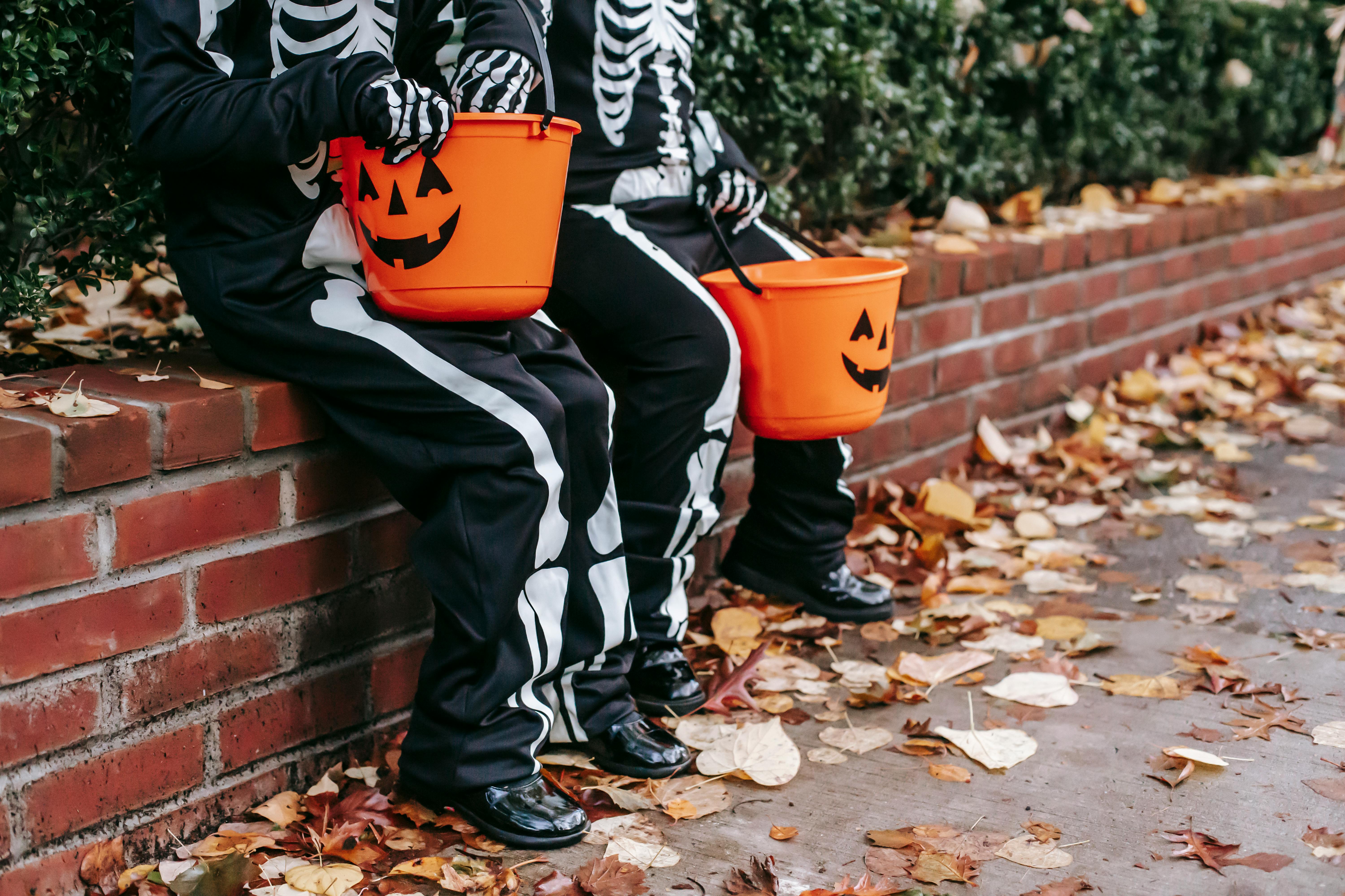 Children in Halloween costumes resting on fence with jack o lantern