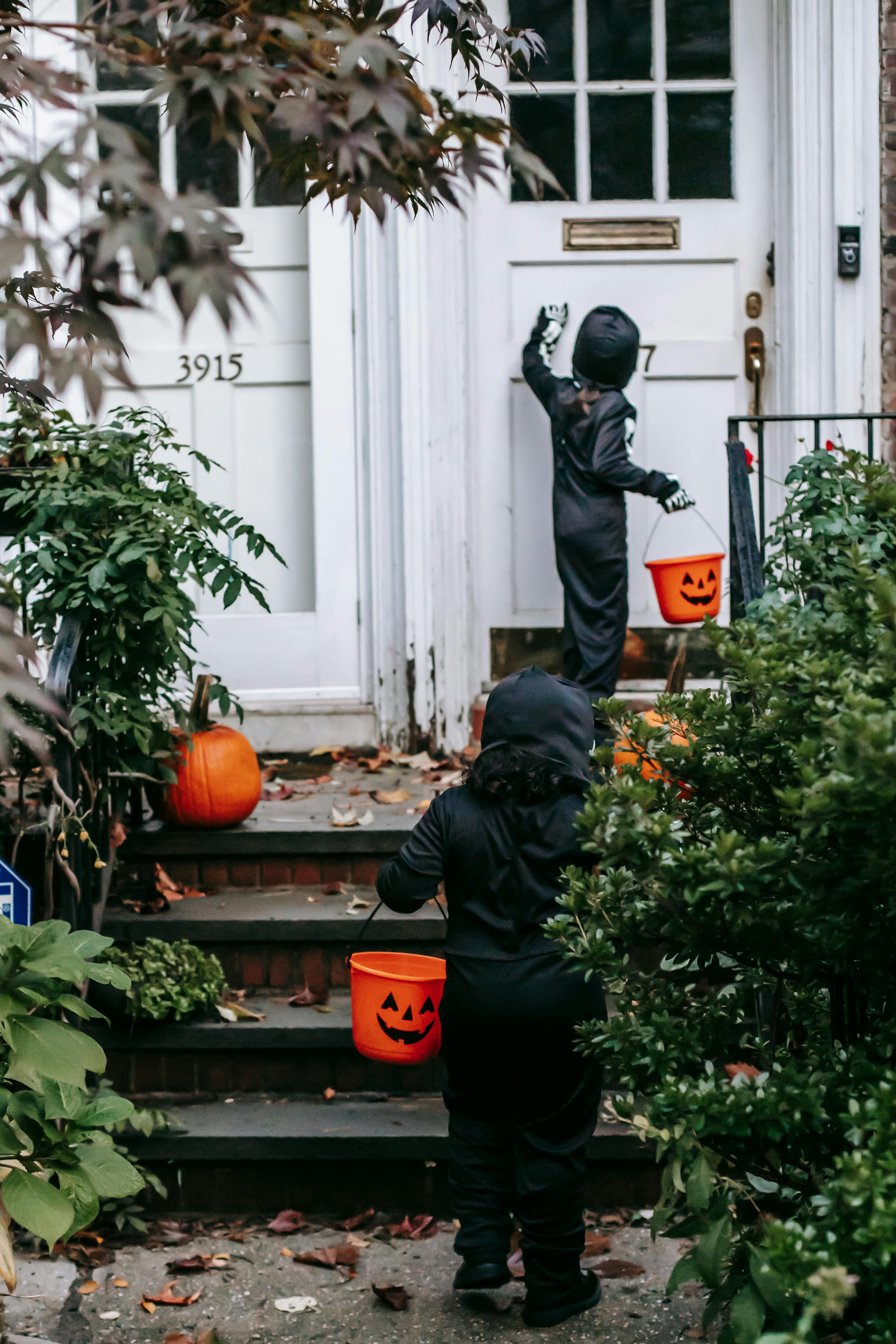 unrecognizable children dressed in black halloween costumes trick or treating