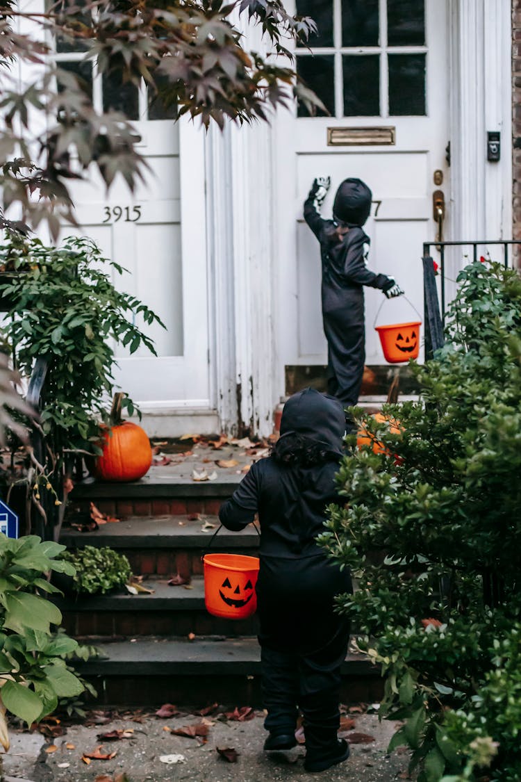 Unrecognizable Children Dressed In Black Halloween Costumes Trick Or Treating