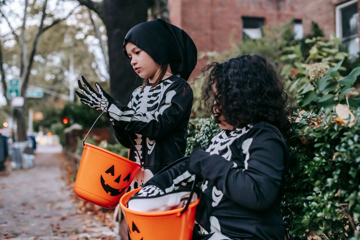 Cute little girls preparing for trick and treat with orange buckets