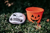 Spooky skeleton mask placed near orange bucket outdoors