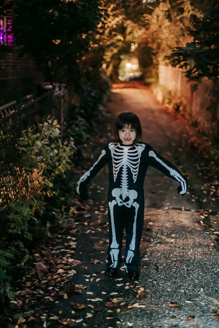 Cheerful Cute Little Girl In Halloween Skeleton Costume In Evening