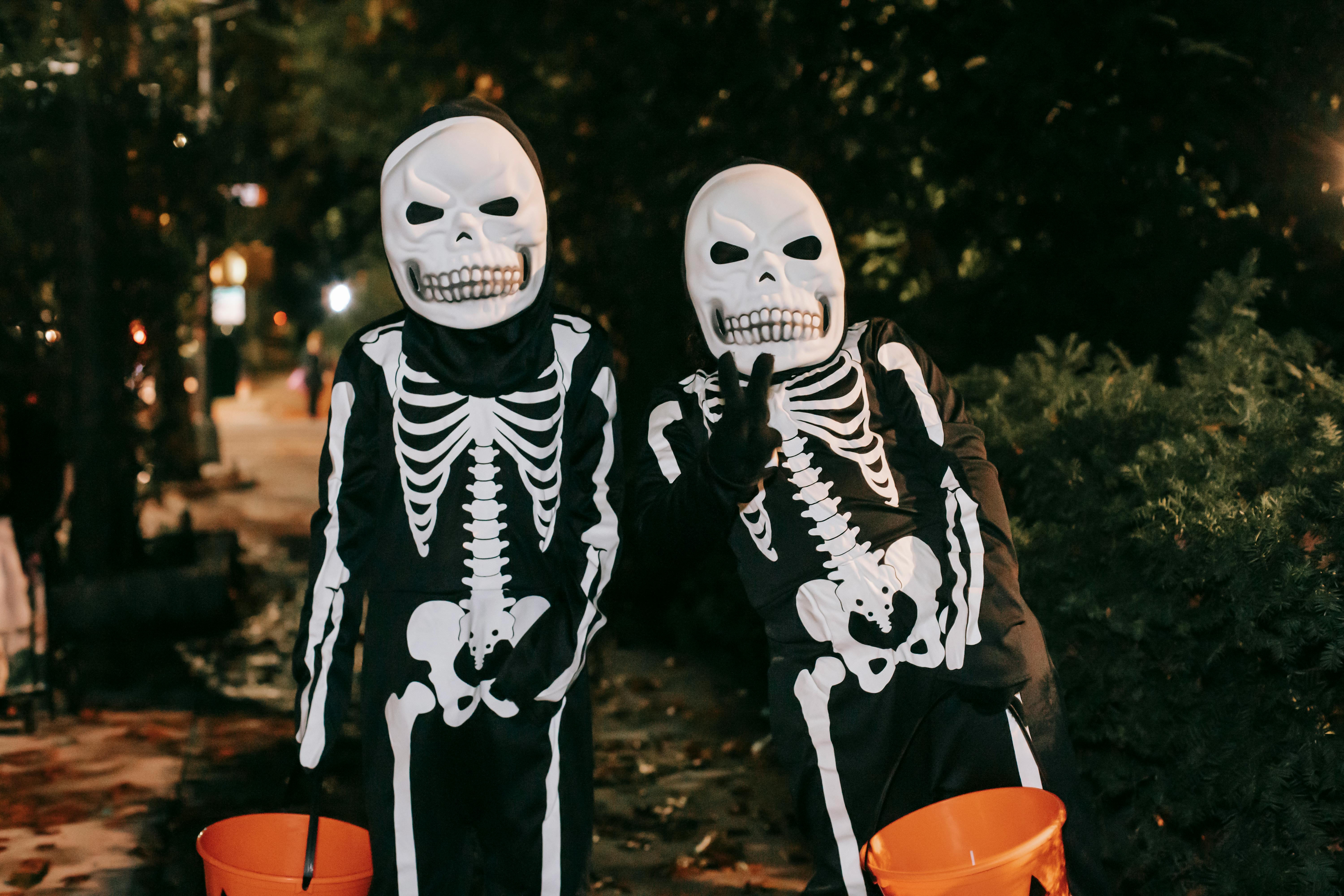 unrecognizable persons in skeleton costumes on street