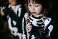 Crop diverse girls with lollipop on Halloween night