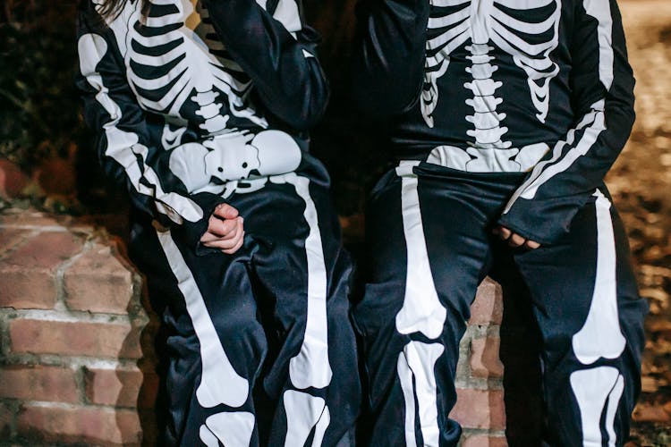 Crop Children In Skeleton Costumes On Halloween Night Outdoors