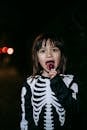 Charming girl enjoying tasty lollypop during Halloween holiday at night