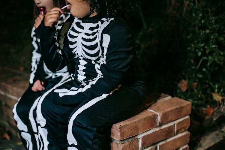 Crop Multiracial Girls Eating Lollies On Halloween Night