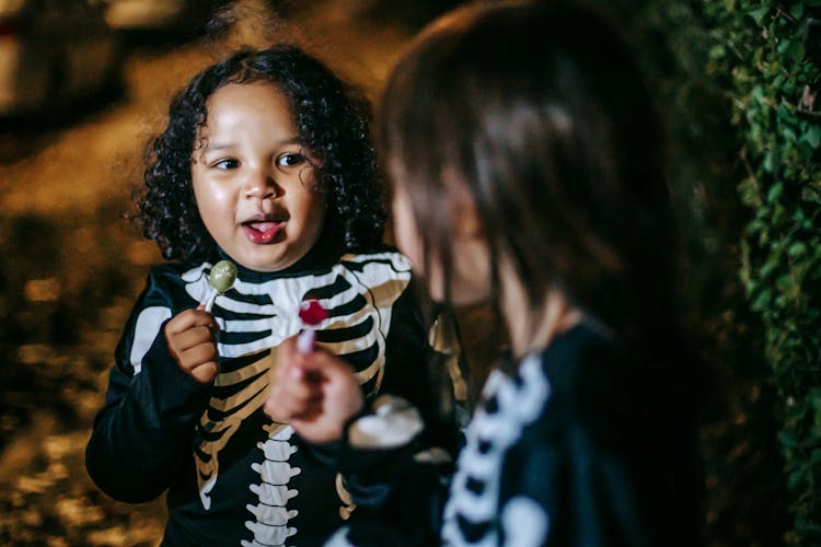 Crop Attentive Multiethnic Girlfriends With Lollies During Halloween Holiday Outdoors