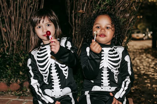 Diverse children with delicious lollipops on Halloween night