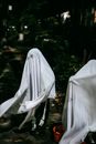 Unrecognizable children wearing spooky ghost costumes while playing together and having fun in lush park