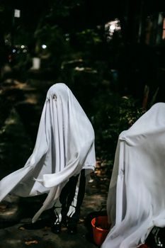孩子们穿着怪异的幽灵服装，面目全非，在郁郁葱葱的公园里一起玩耍