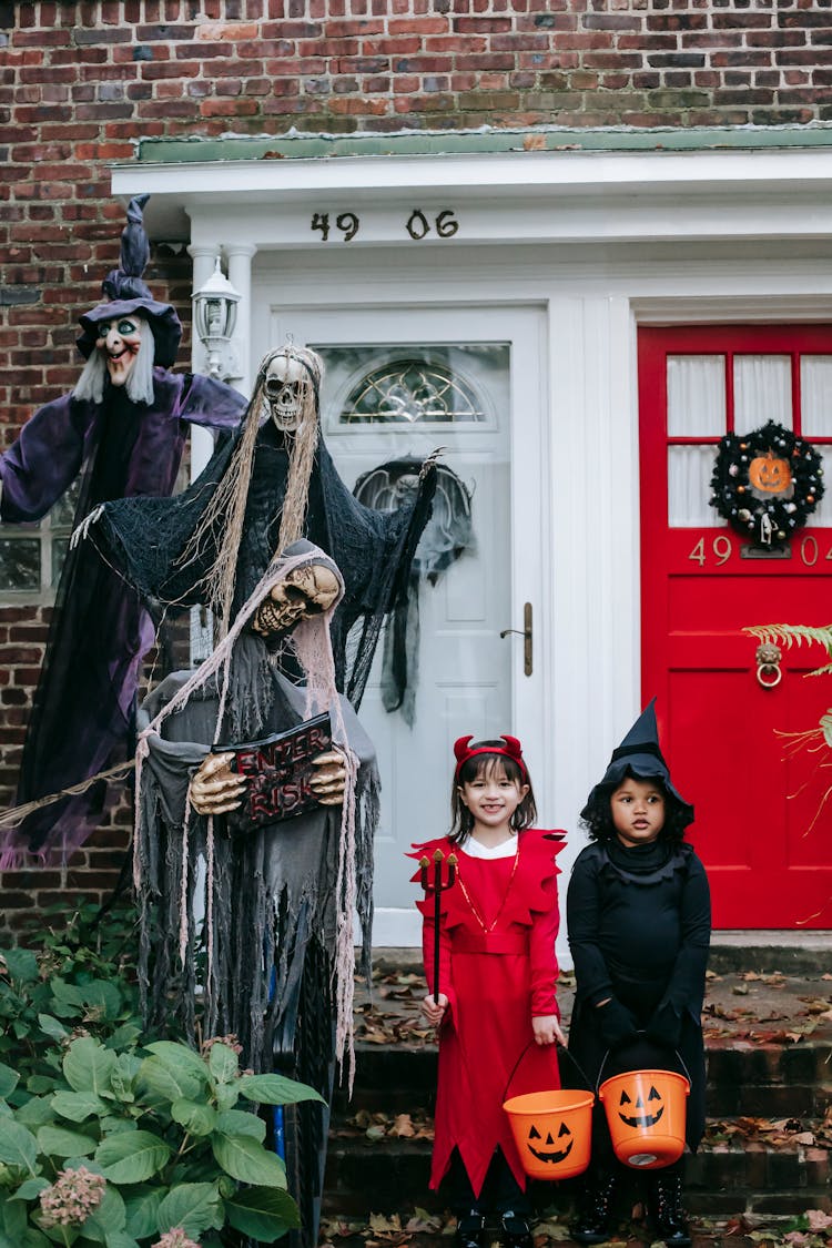 Cute Girls In Halloween Costumes Standing Outside Modern House