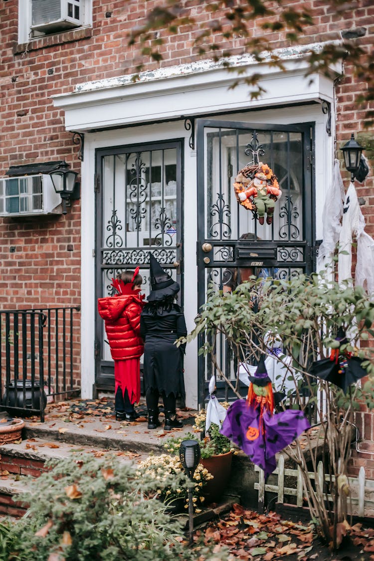 Unrecognizable Kids In Halloween Costumes Knocking On House Door