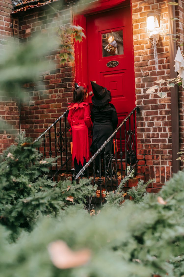 Unrecognizable Kids In Halloween Costumes Knocking On House Door