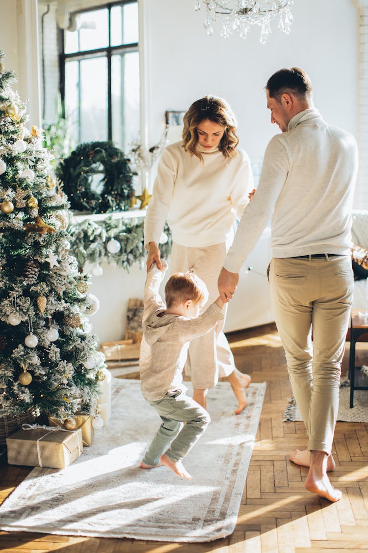 Family Dancing Beside A Christmas Tree