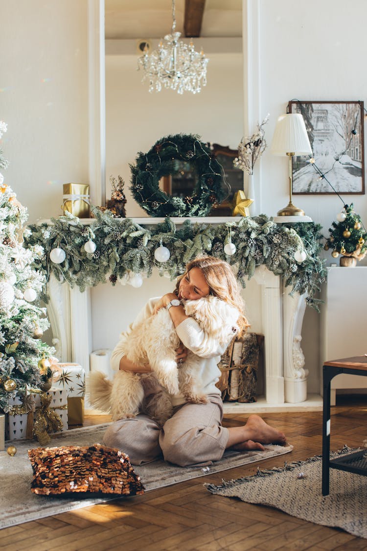 Woman Hugging A Pet Dog Near The Christmas Tree