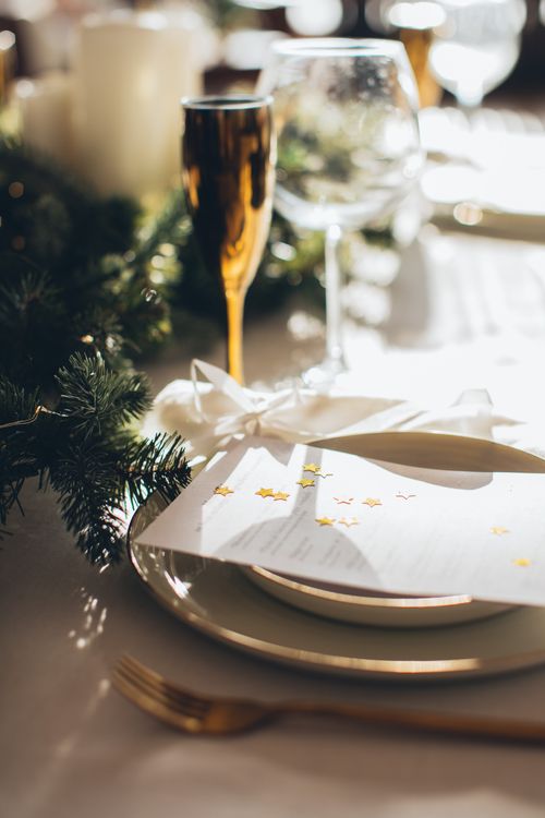 Free Festive table setting featuring elegant gold accents and green foliage, perfect for holiday celebrations. Stock Photo