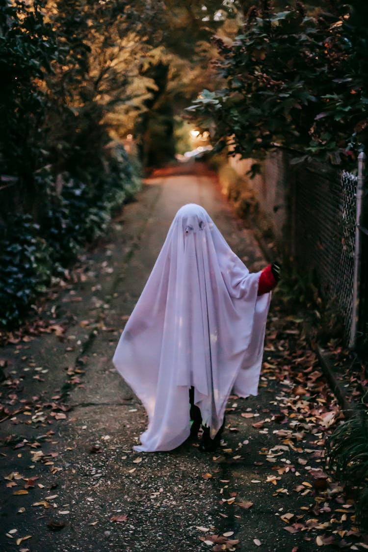 Unrecognizable Kid In Ghost Costume Walking On Walkway