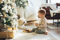 孩子和狗在室内一棵装饰精美的圣诞树旁共度圣诞时光
