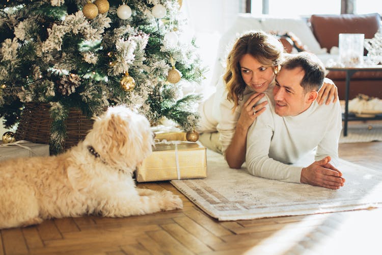 Couple Lying On A Carpet Near Their Dog