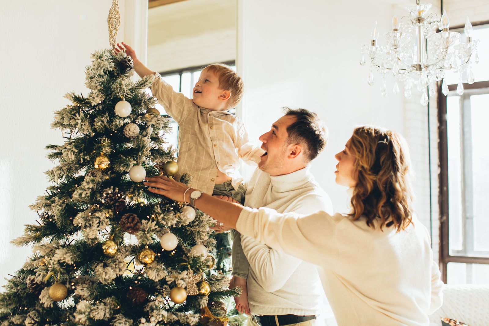 Family decorating a Christmas tree together at home.