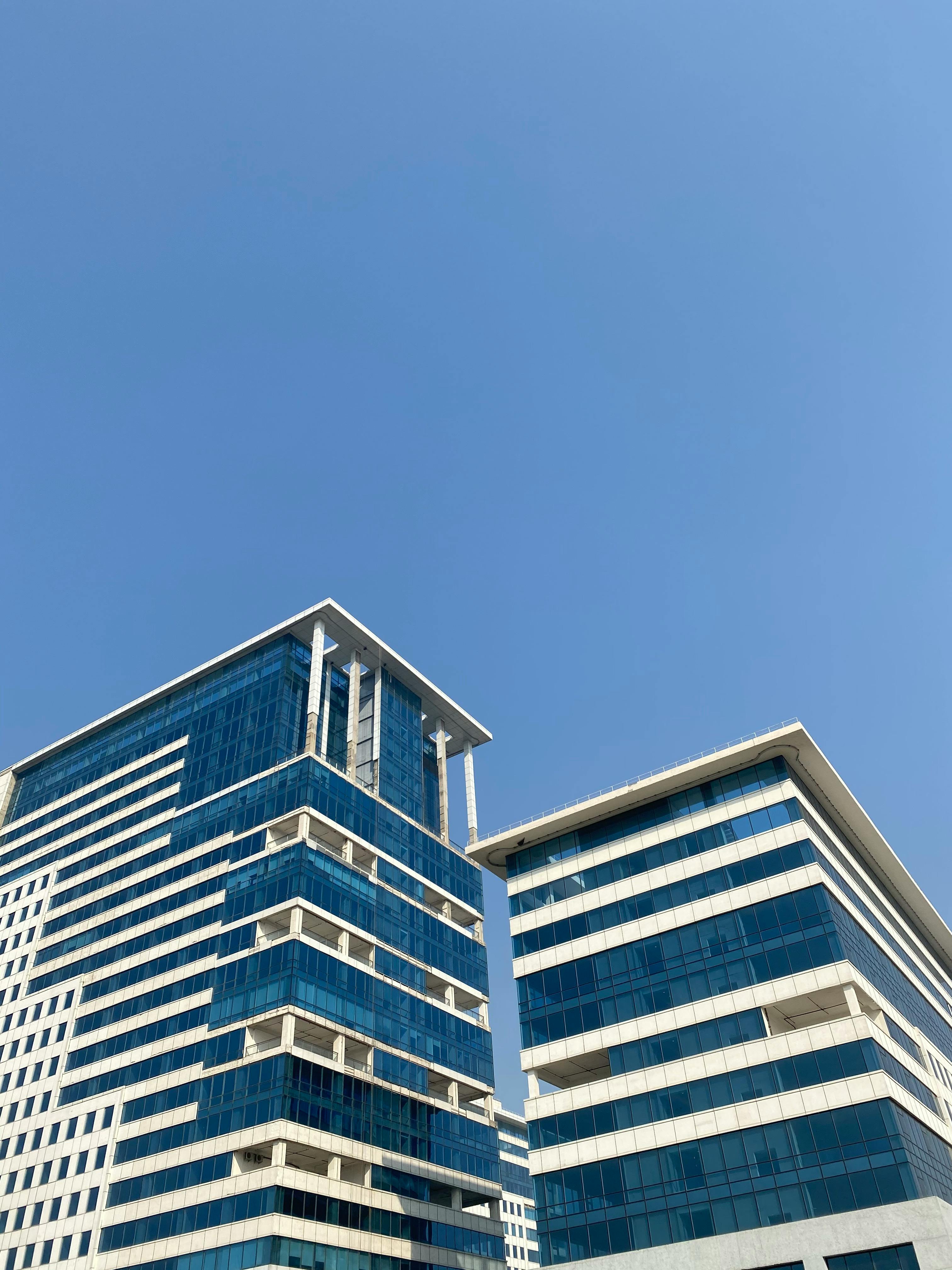 Low angle view of contemporary office buildings against a bright blue sky in Gurugram, India.
