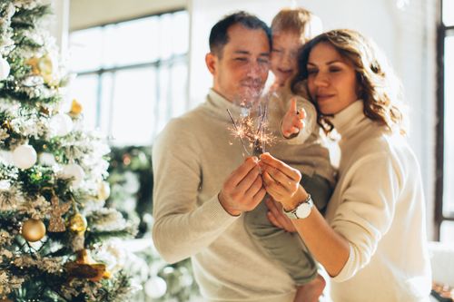 Free Happy family enjoying Christmas celebrations at home with sparklers, creating a joyful atmosphere. Stock Photo