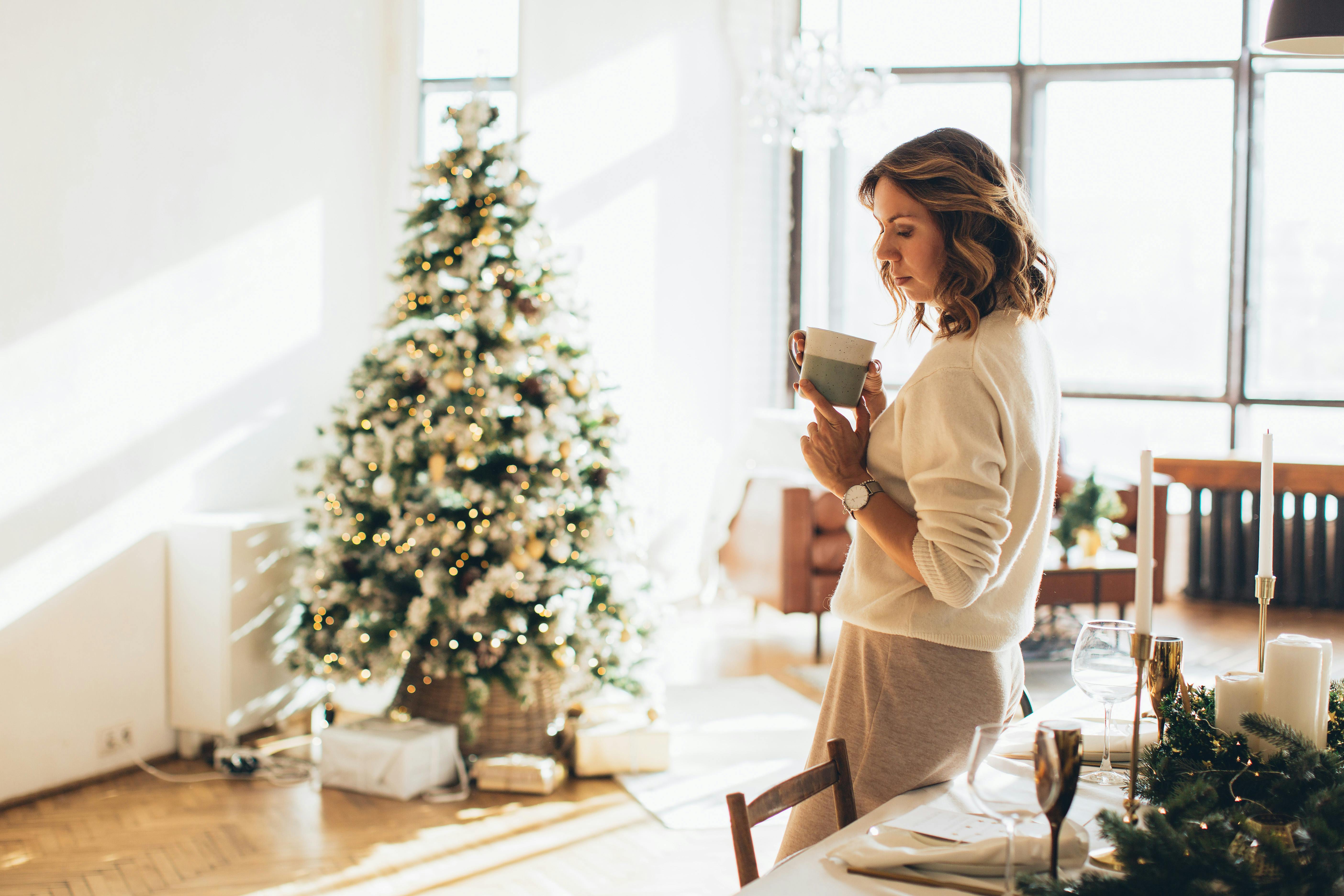 Woman relaxing with coffee by Christmas tree in cozy holiday setting