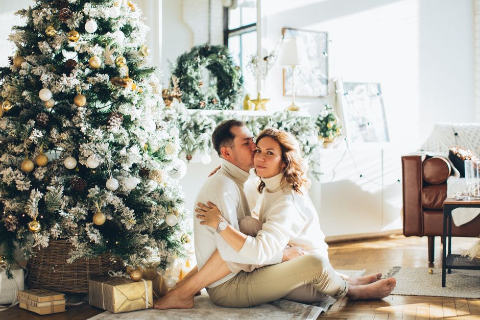 personalized home decor gifts - A couple sitting by the Christmas tree in a warmly lit living room, embracing the holiday spirit.