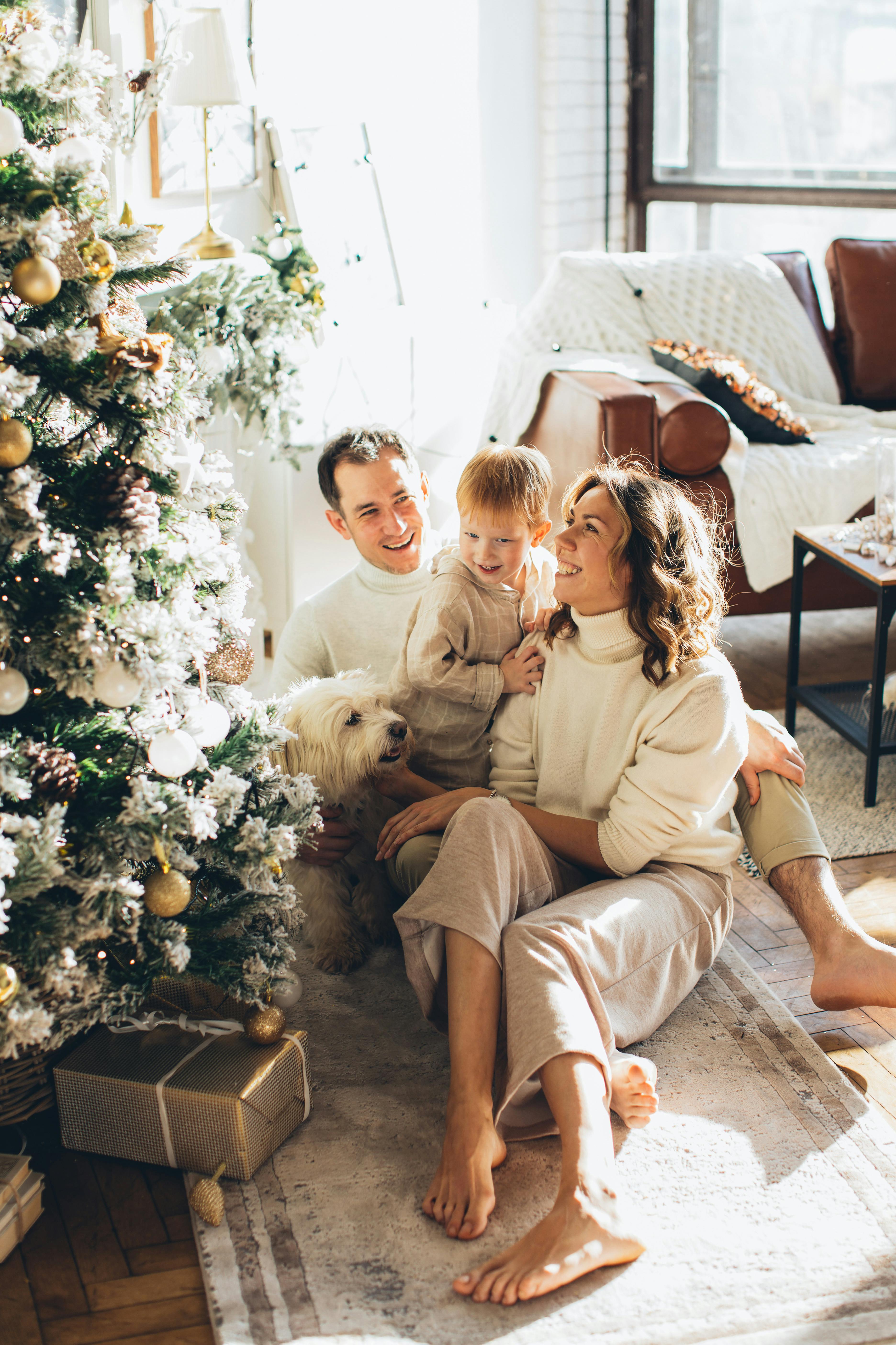 a happy family sitting beside a christmas tree