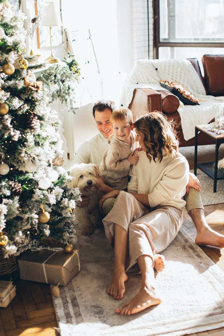 Smiling Family Sitting By Christmas Tree