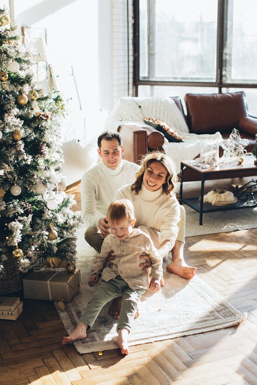 Photo of a Happy Family Sitting Beside the Christmas Tree