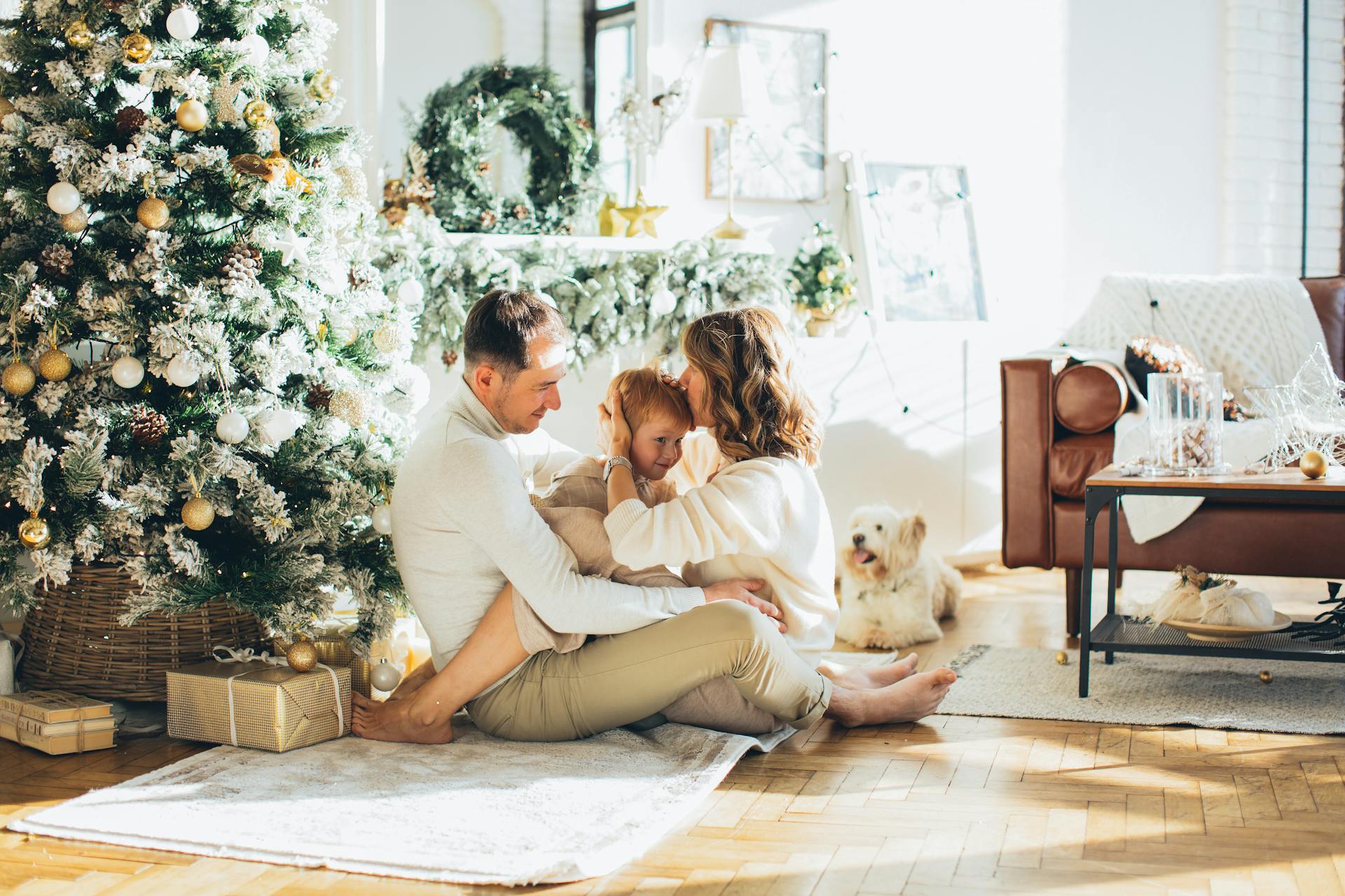 Photo of a Happy Family Sitting Beside the Christmas Tree with Their Dog