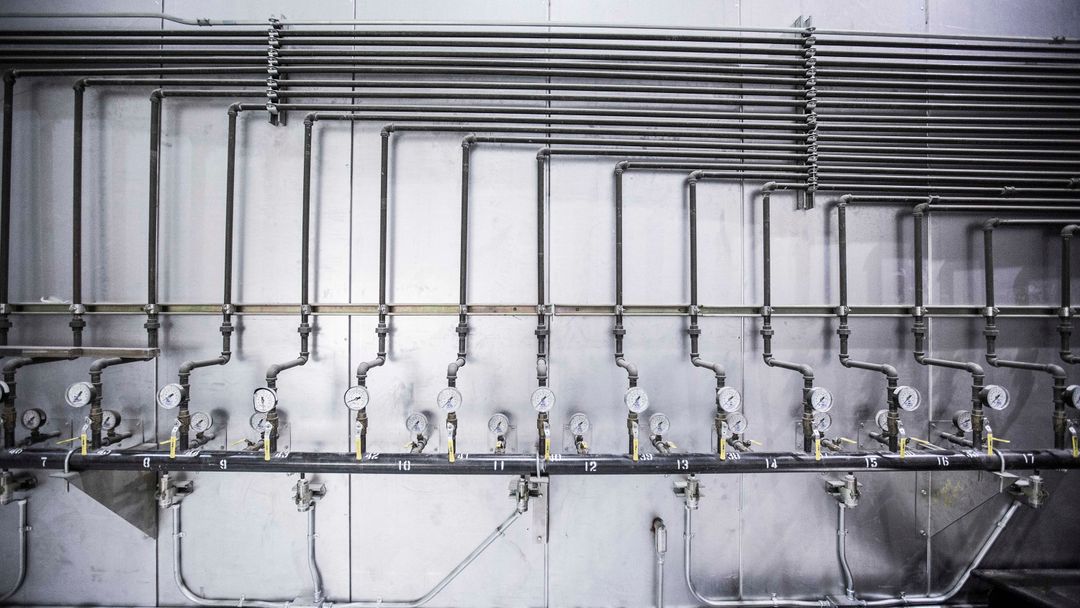 A pressure gauge on pipework. On a stored supply, the pump and the gauge are what make it behave like an ordinary house.