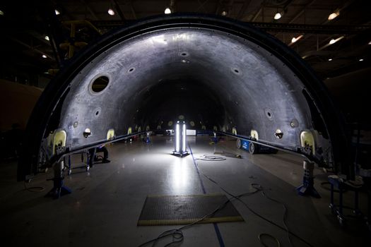 Illuminated tunnel with rocket construction equipment and lights in dark contemporary spacious industrial factory