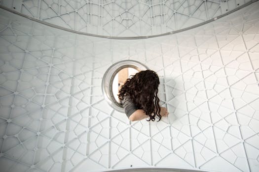 一个女人透过现代几何结构的圆形开口凝视，流露出一种好奇心