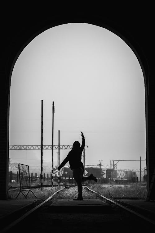 Silhouette of Woman Dancing on a Railway in Grayscale Photography