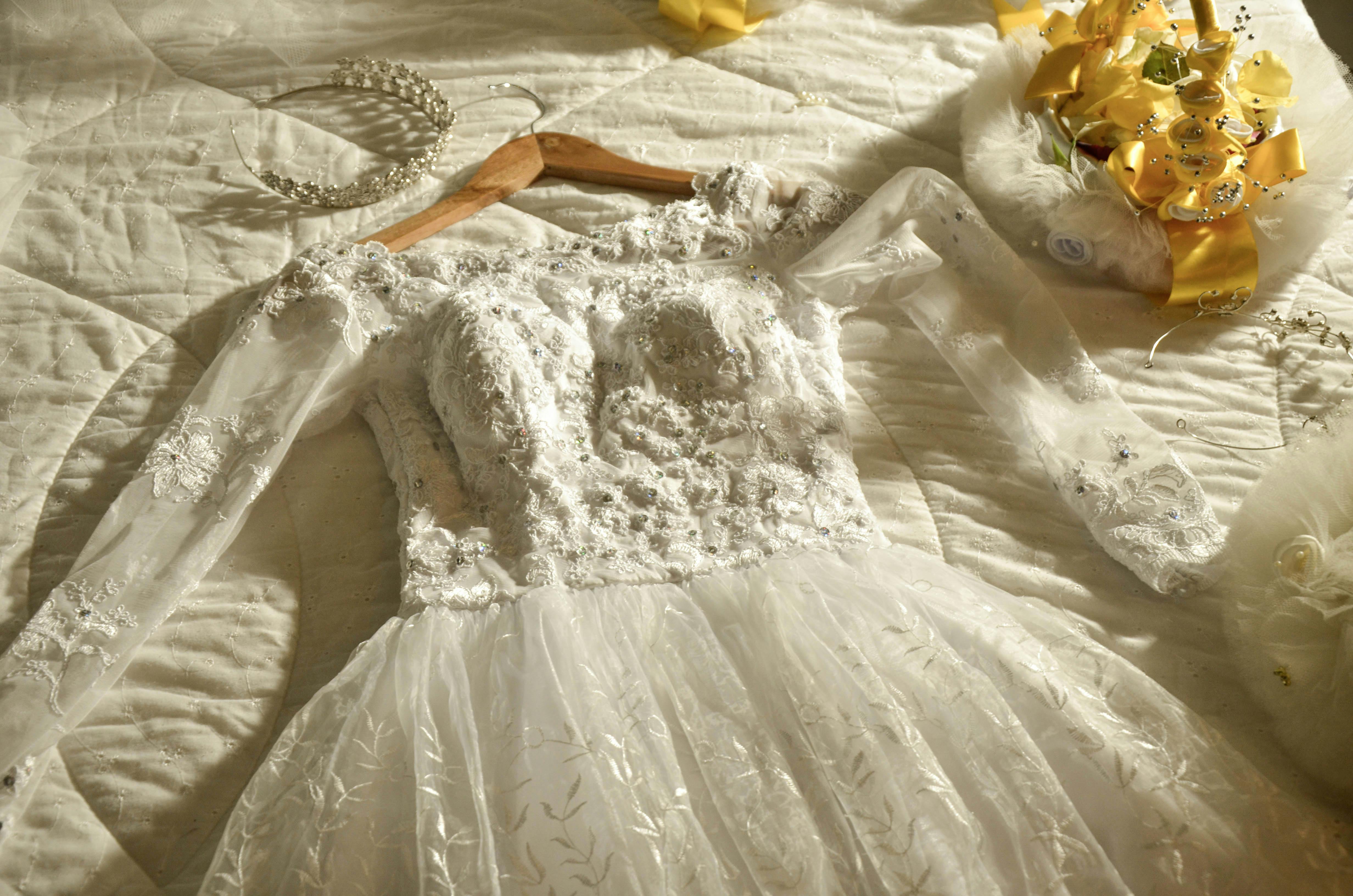 Beautiful lace bridal gown with tiara laid on bed, perfect for wedding themes.