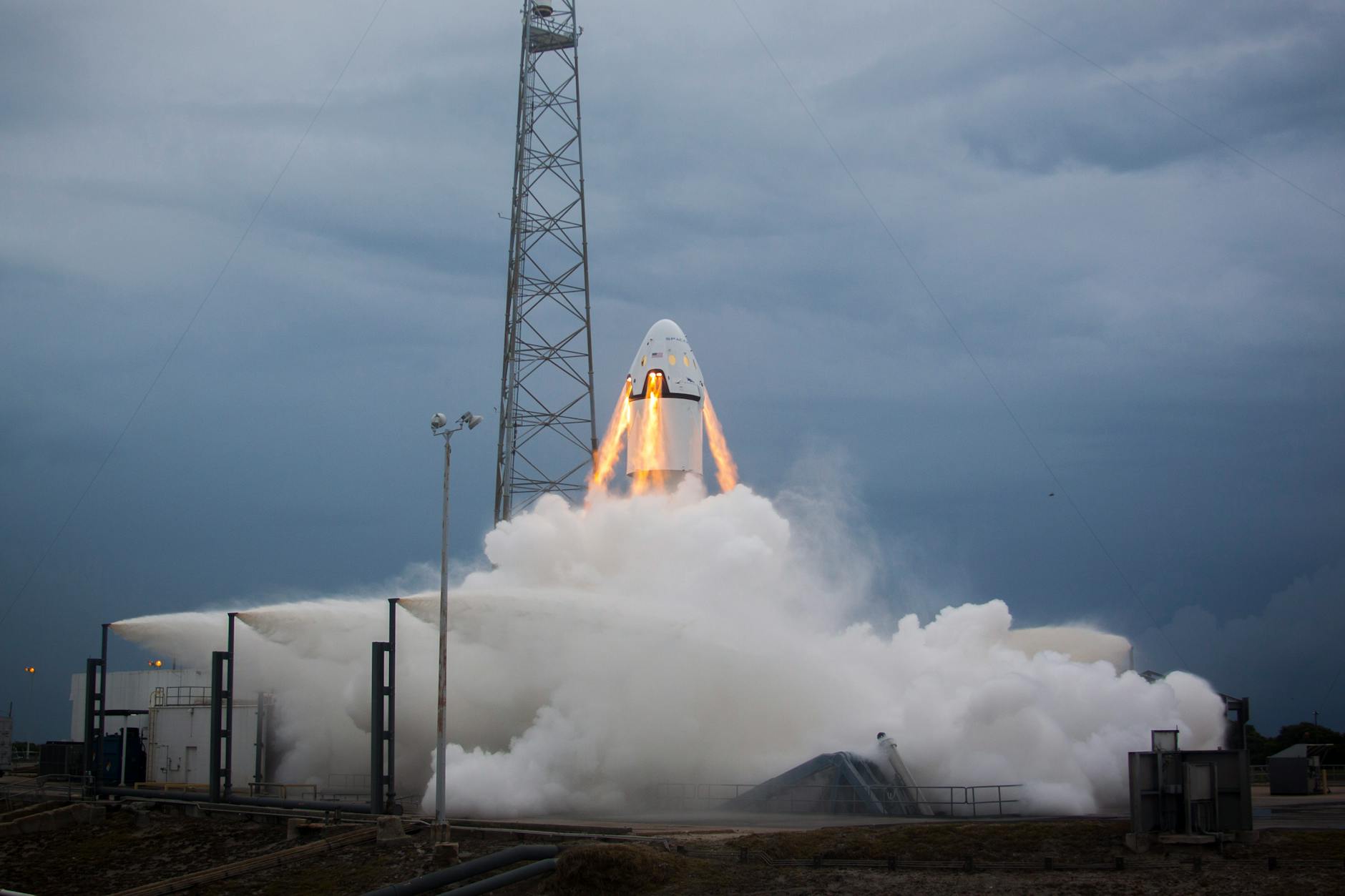 A dramatic rocket launch emitting flames and smoke against a cloudy evening sky, showcasing modern aerospace technology.