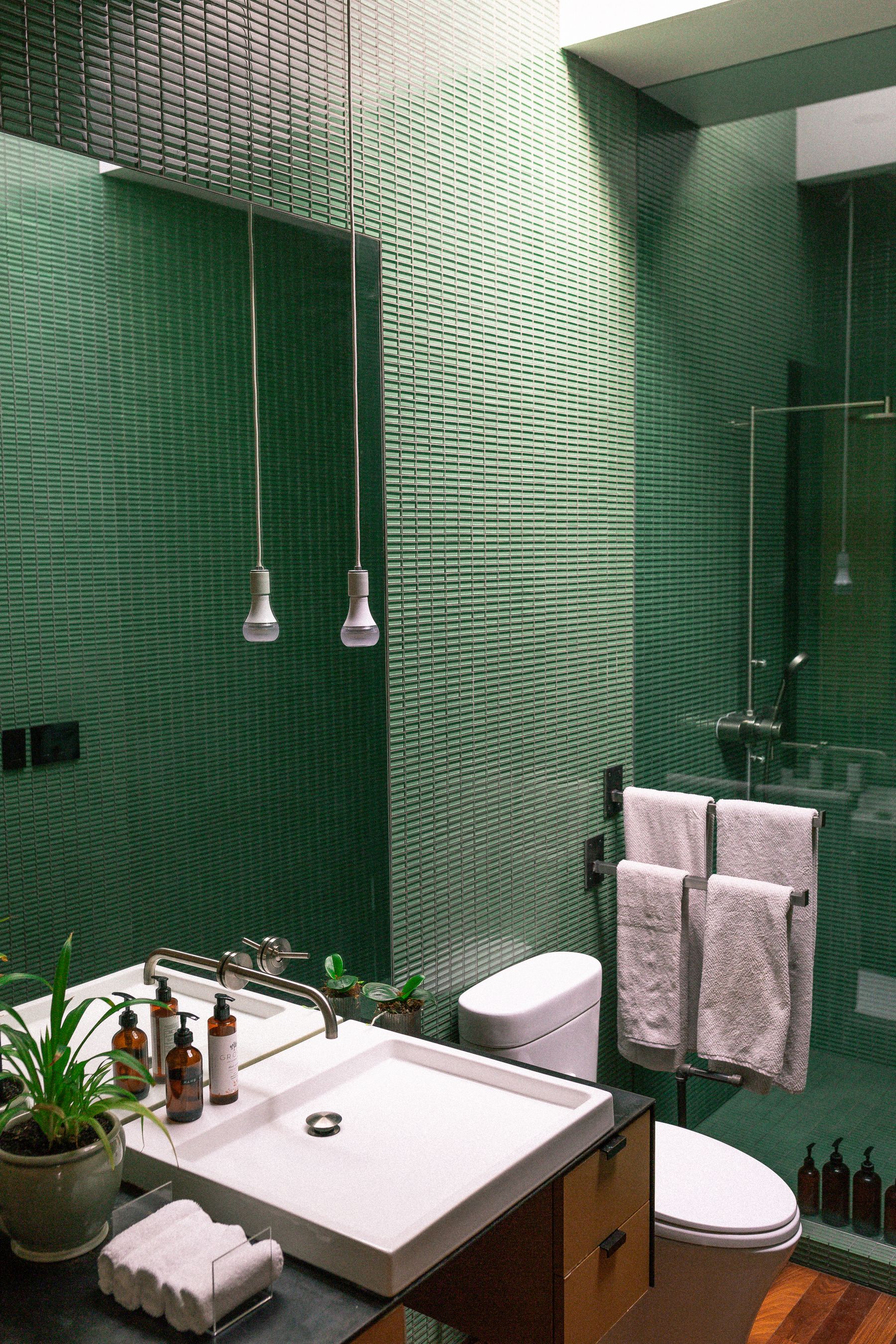 Green tiled room with one potted plant and restrained contemporary fixtures
