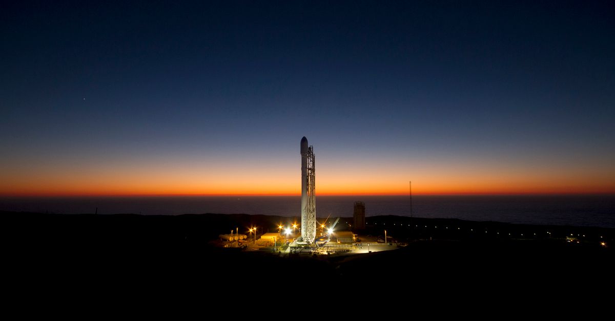A powerful rocket stands ready on its launch pad against a stunning twilight sky.