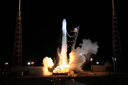 Modern solid rocket taking off into dark night sky during launching from spaceport