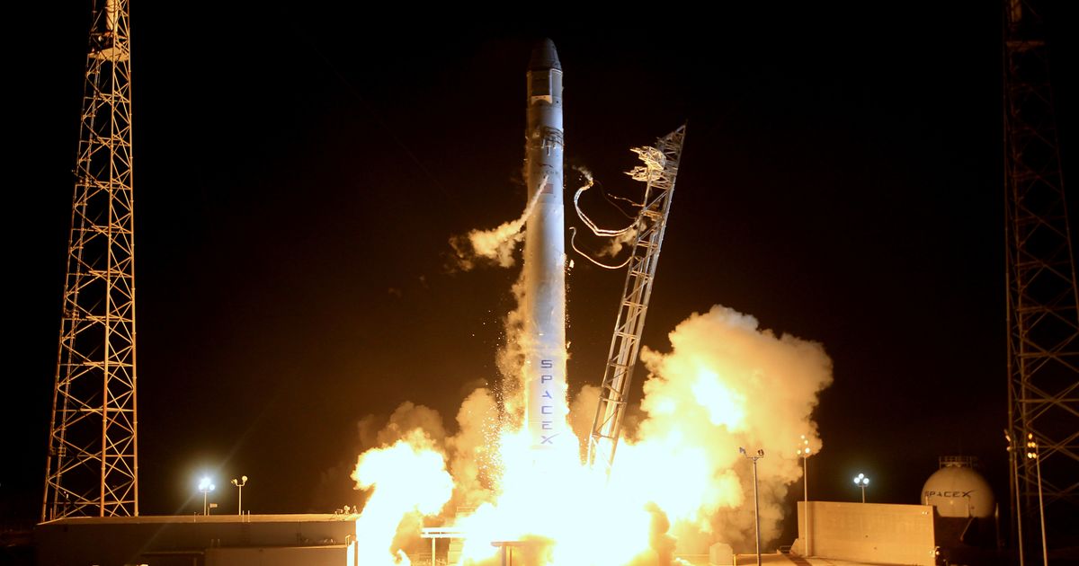 A rocket lifting off at night with flames and smoke lit against the dark.