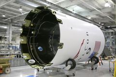 From below of exterior detail of rocket with inscription and American flag placed on rolling platform at modern factory