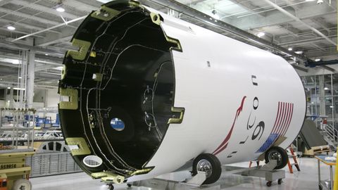 From below of exterior detail of rocket with inscription and American flag placed on rolling platform at modern factory