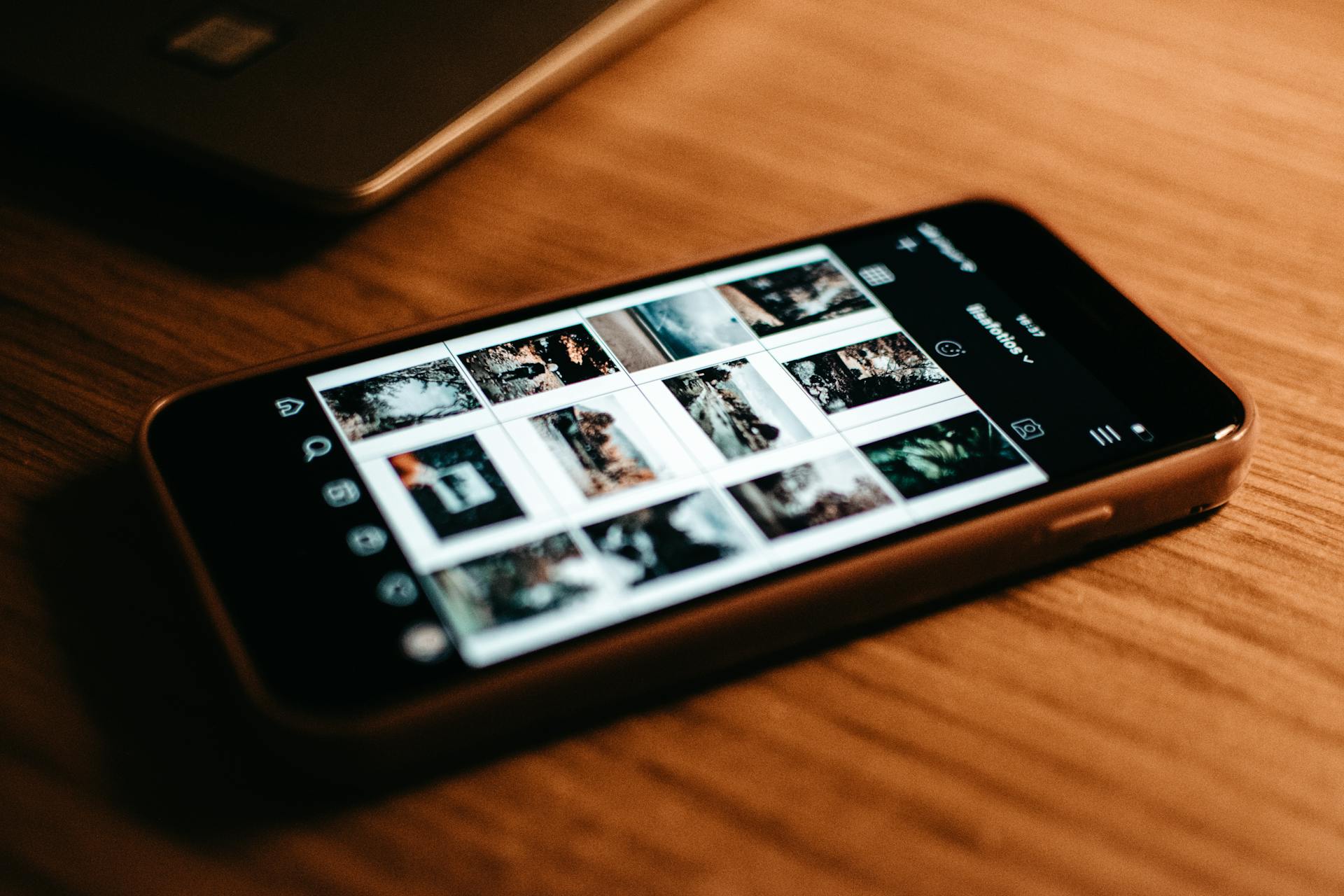 Close-up of smartphone showing photo gallery on wooden desk.