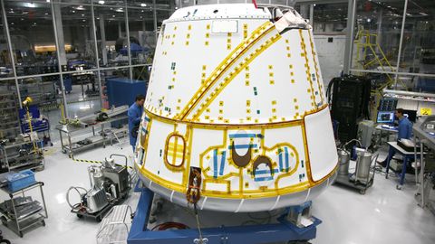 Anonymous male mechanic in uniform fixing detail of spacecraft while working at modern headquarter of industrial factory