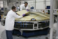 Professional mechanics installing spaceship detail at factory